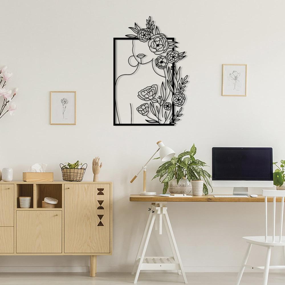 A study area showcasing a metal wall art piece of a woman with roses and leaves, mounted on the wall above a Scandinavian-style wooden desk, creating a serene workspace environment.
