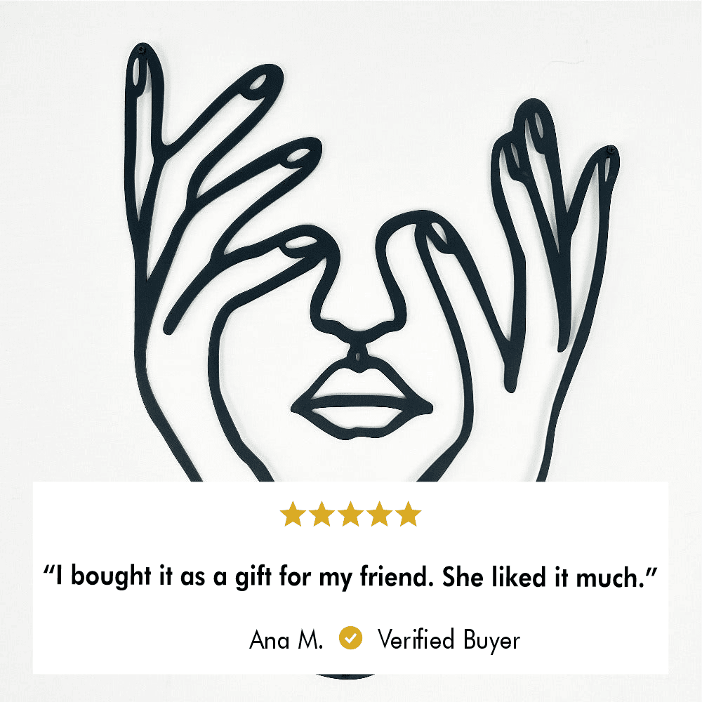 Minimalist metal wall art of a woman's face with hands framing it on a white background. A verified buyer review below states, "I bought it as a gift for my friend. She liked it much," rated 5 stars by Ana M.