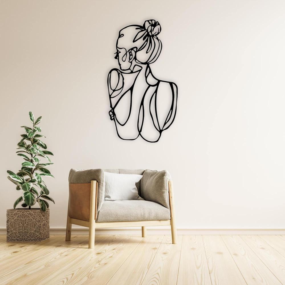 A minimalist reading corner with a black metal wall art of a woman’s figure, placed above a cozy armchair next to a leafy indoor plant.