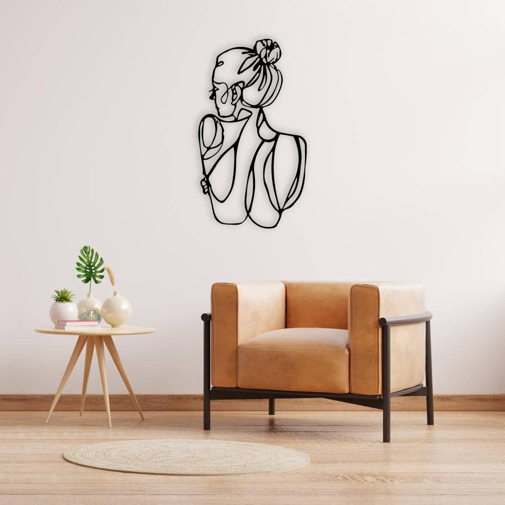 A contemporary room with a black metal wall art of a minimalist woman's figure, mounted on a light wall above a tan leather armchair, next to a round wooden side table adorned with decorative vases and a small plant.
