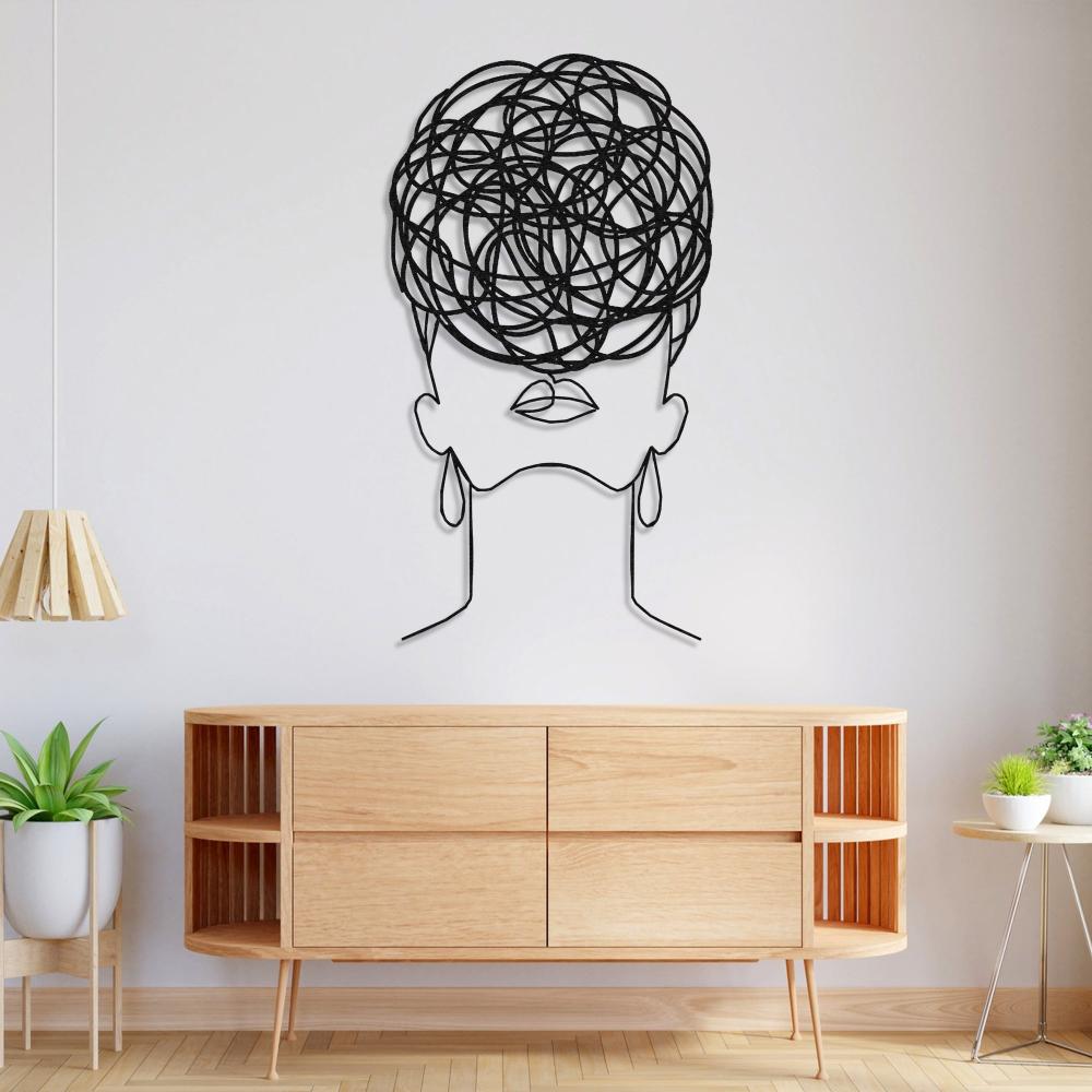 Artistic wall decor of a woman's silhouette with circular pattern hair, mounted above a modern wooden sideboard with minimal decor.