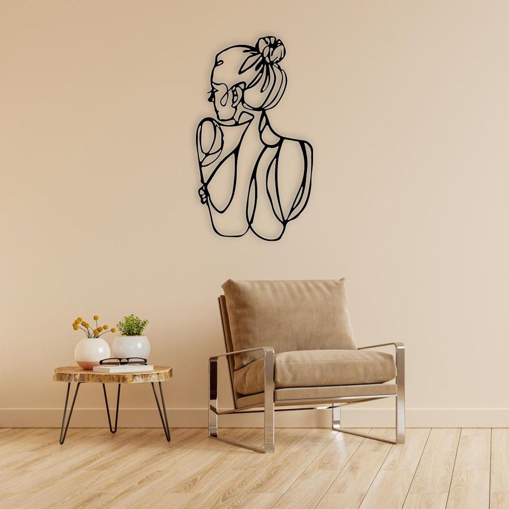 A chic interior setting with a black metal wall art of a woman’s figure, mounted above a tan leather armchair beside a wooden side table.