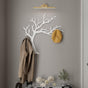 Tree branch shaped coat rack in white metal with wall mounted hooks.
