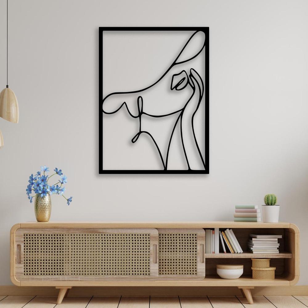 Abstract woman with a hat black metal wall art displayed above a wooden console table decorated with blue flowers and books.