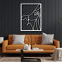 Minimalist white metal wall art of an abstract woman with a hat, mounted on a black paneled wall above an orange couch with modern decor.
