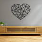 Minimalist geometric heart-shaped metal wall art in black, mounted on a light gray wall above a modern wooden console, with a small plant and a pair of glasses for decor.