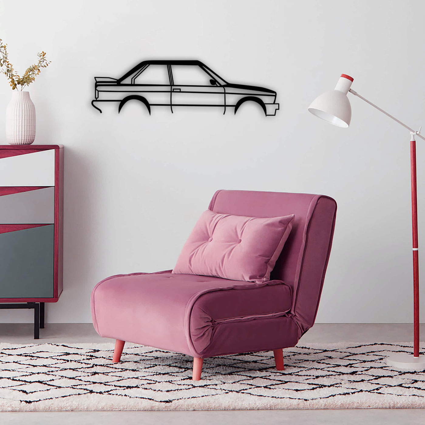 BMW E30 car silhouette metal wall art displayed on a pink wall beside a modern accent chair.