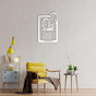 A cozy reading corner with a yellow accent chair, a side table holding small potted plants, and a white "Cactus in Vase" metal wall art mounted on a beige wall.