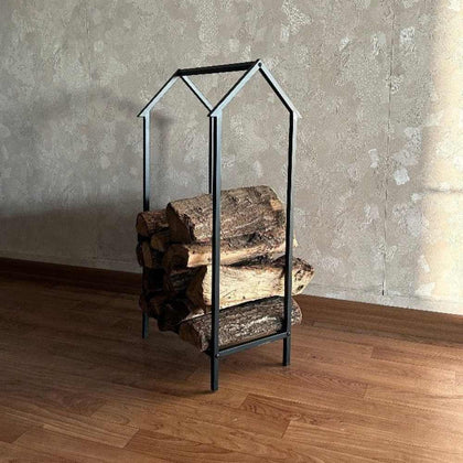 Portable Home Shaped Metal Log Storage in a minimalist house silhouette, neatly stacked with logs, displayed on a warm wooden floor with a textured rug