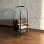 Portable Home Shaped Metal Log Storage in a minimalist house silhouette, neatly stacked with logs, displayed on a warm wooden floor with a textured rug