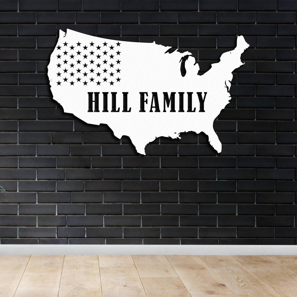 White metal wall art of the USA map with the text "Hill Family" displayed on a dark brick wall for a contrasting decor style.