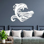 White metal wall art featuring a stylized dolphin jumping over ocean waves with an island silhouette, mounted on a navy blue wall above a gray modern sofa with white cushions and a green plant on a side table.