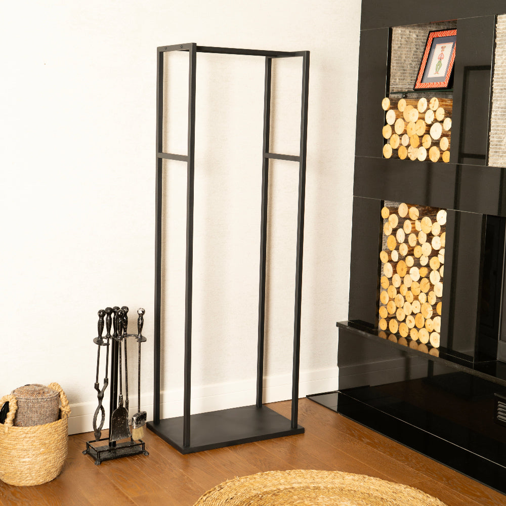 Black freestanding fireplace screen in a room with firewood and tools.