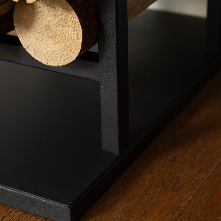 Close-up of a black fireplace with stacked logs on a wooden floor