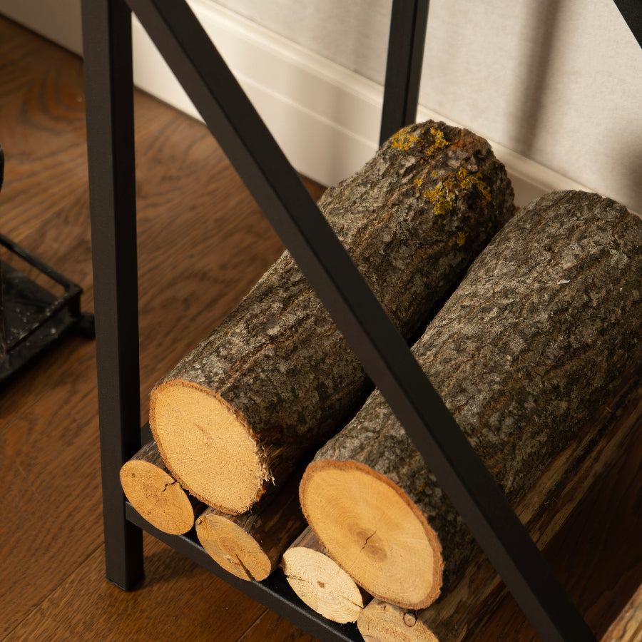 Wooden logs stacked on a metal log holder against a white curtain.