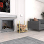 A gold metal firewood rack with a geometric design placed beside a modern fireplace, loaded with neatly stacked firewood, in a cozy living room setting.