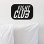 Fight Club-themed black metal wall art with bold 3D typography, mounted above crisp white pillows on a minimalist white wall.