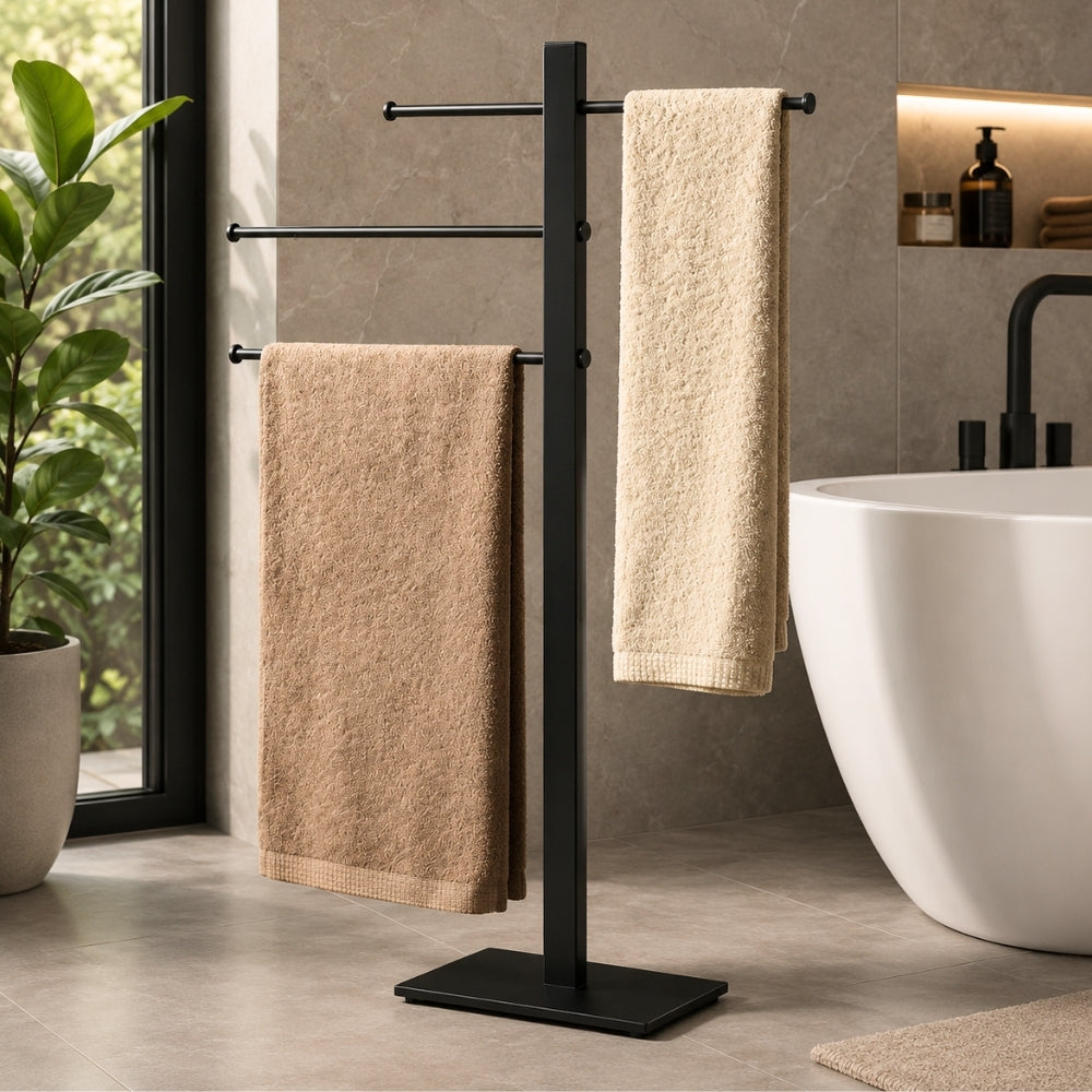 Black freestanding 3-bar towel stand holding towels beside a bathtub in a modern bathroom.