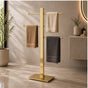 Gold freestanding 3-bar towel stand holding towels in a modern bathroom.