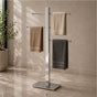 Satin nickel freestanding 3-bar towel stand holding towels in a modern bathroom.