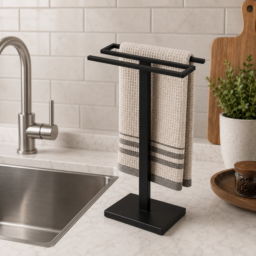 Black freestanding countertop double towel holder with hand towel beside a kitchen sink.