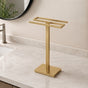 Gold freestanding countertop double towel holder on a light bathroom vanity.