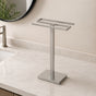 Satin nickel freestanding countertop double towel holder on a light bathroom vanity.