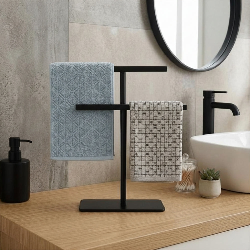 Black freestanding countertop towel holder with blue and gray towels on a modern bathroom vanity.