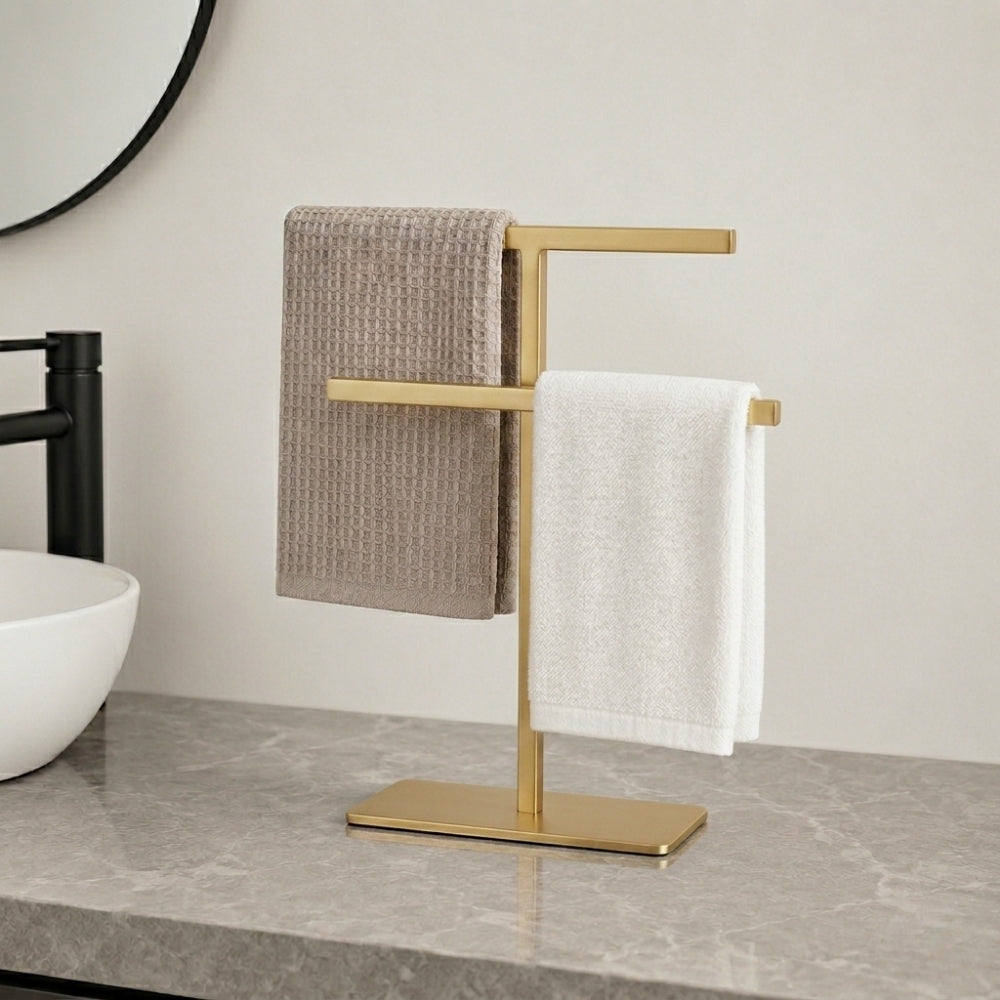 Gold freestanding countertop towel holder with beige and white towels on a bathroom vanity.