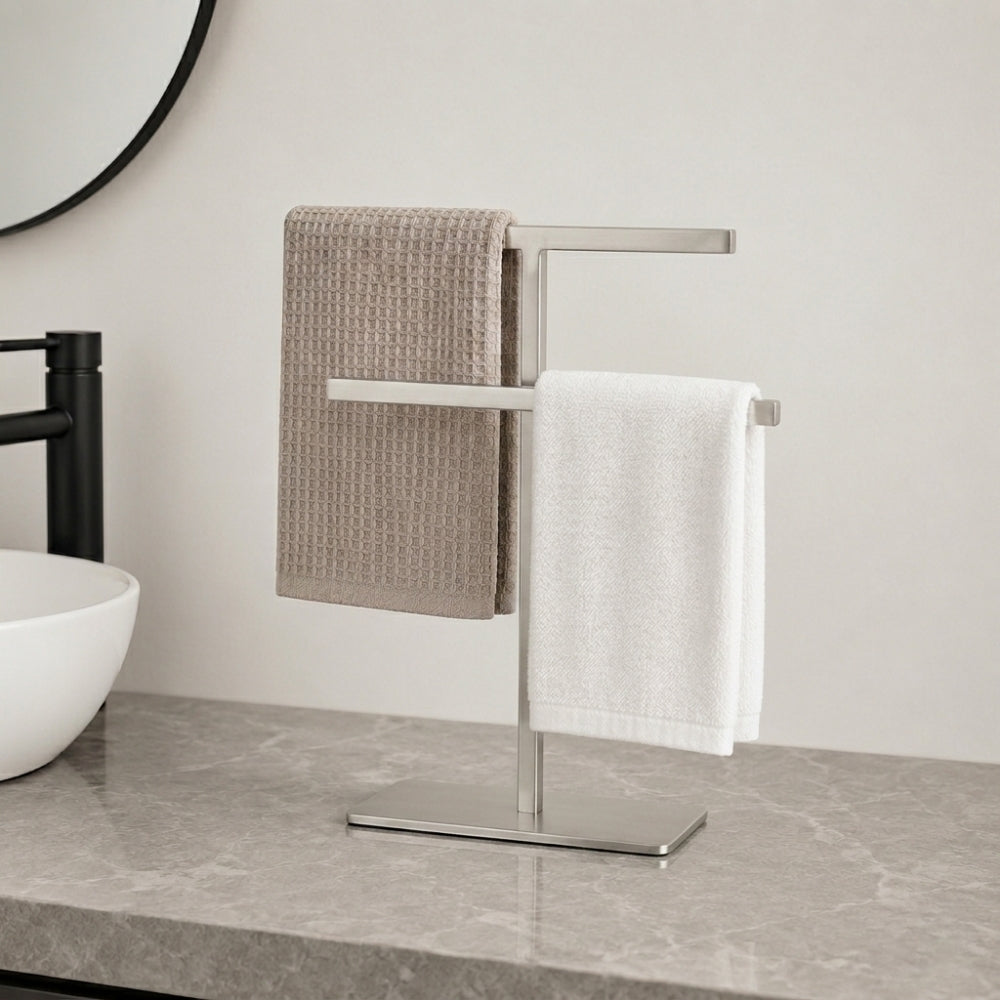 Satin nickel freestanding countertop towel holder with white towels on a bathroom counter.