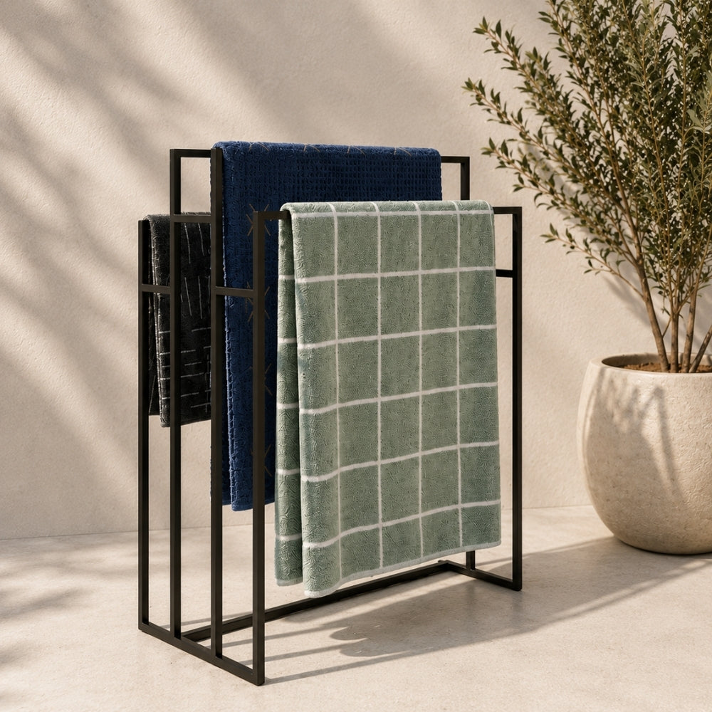 Black freestanding outdoor pool towel rack with multiple towels hanging on separate rails.