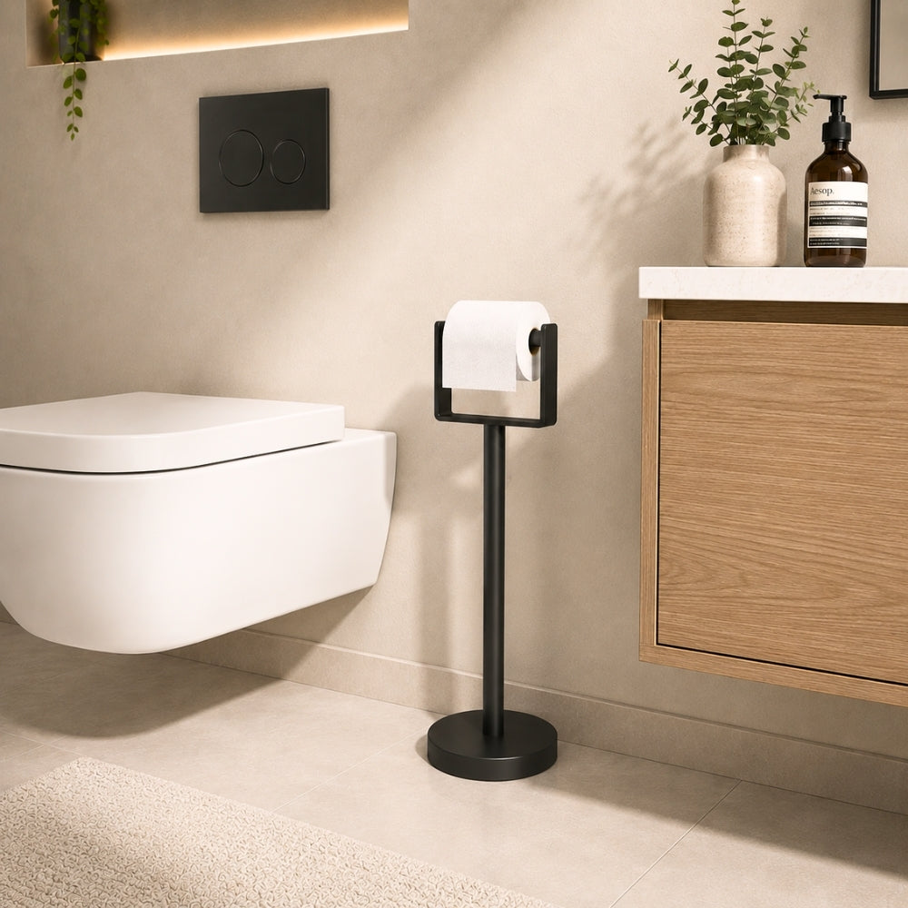 Black freestanding toilet paper holder stand beside a modern bathroom toilet and vanity.