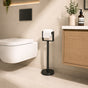 Black freestanding toilet paper holder stand beside a modern bathroom toilet and vanity.