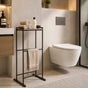 Black freestanding towel rack with top shelf in a modern bathroom beside a shower.
