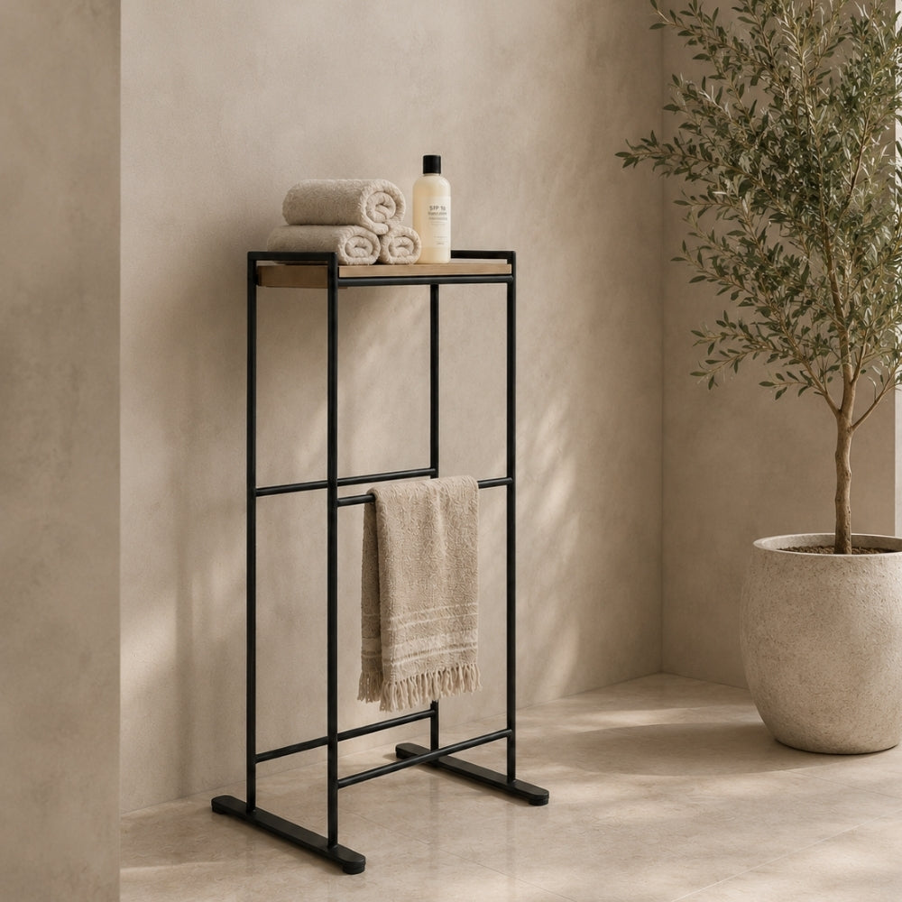 Black freestanding towel rack with top shelf holding folded towels and a hanging towel.