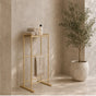 Gold freestanding towel rack with top shelf holding folded towels and a hanging towel.