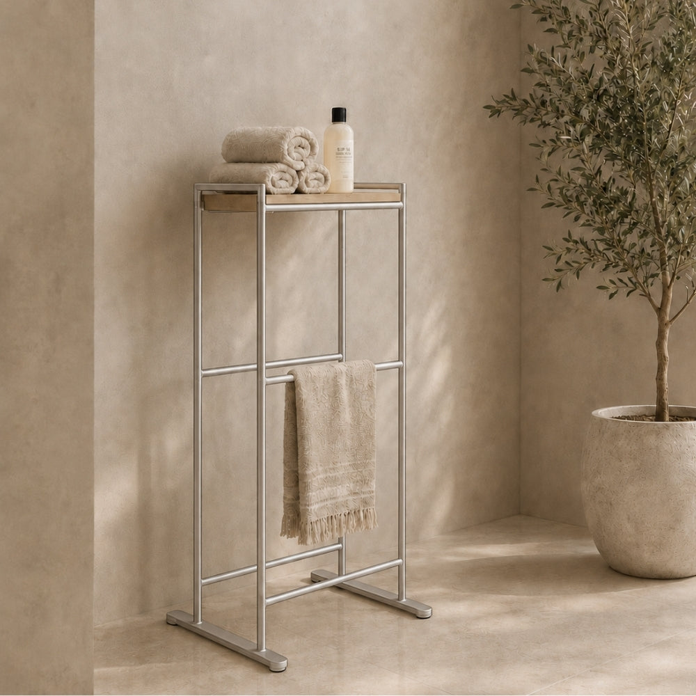 Satin nickel freestanding towel rack with top shelf holding folded towels and a hanging towel.