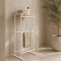 White freestanding towel rack with top shelf holding folded towels and a hanging towel.