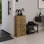 Gold geometric lattice metal umbrella stand in modern entryway with shoe bench and warm decor