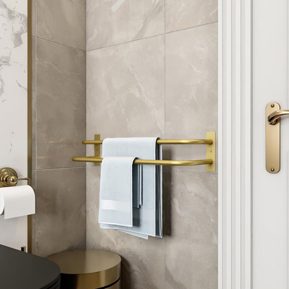 A luxurious gold double-bar towel holder mounted in a modern bathroom, showcasing folded blue towels. The image highlights the elegant combination of gold accents, neutral-colored tiles, and a stylish door handle for a sophisticated design.