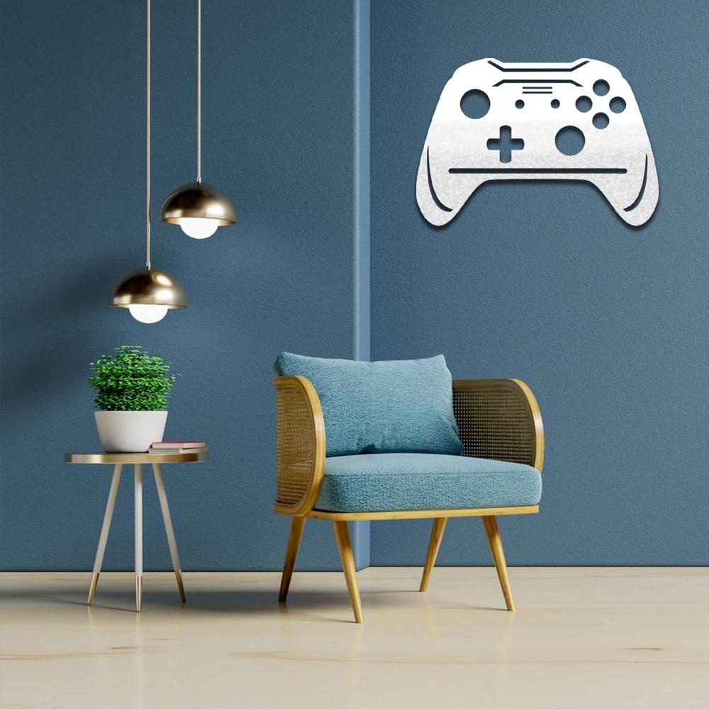 Wall-mounted white joystick-shaped metal wall art displayed on a blue wall, complemented by a cozy armchair and a modern side table with a potted plant, creating a gaming-inspired decor.