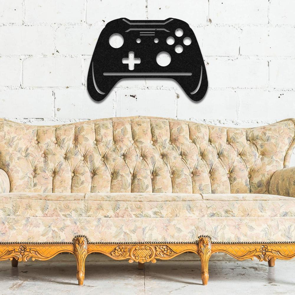 Black joystick-shaped metal wall art mounted on a white brick wall, placed above a vintage floral-patterned tufted sofa with ornate wooden legs, blending gaming style with classic decor.