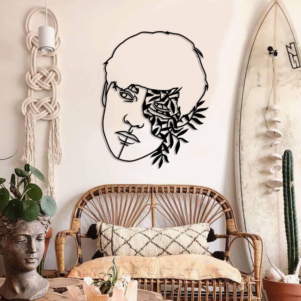 A black metal wall art piece showcasing a man's face and floral patterns, mounted on a wall in a contemporary living room.