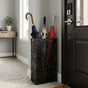Black leaf pattern metal umbrella stand in modern entryway holding multiple umbrellas with handles