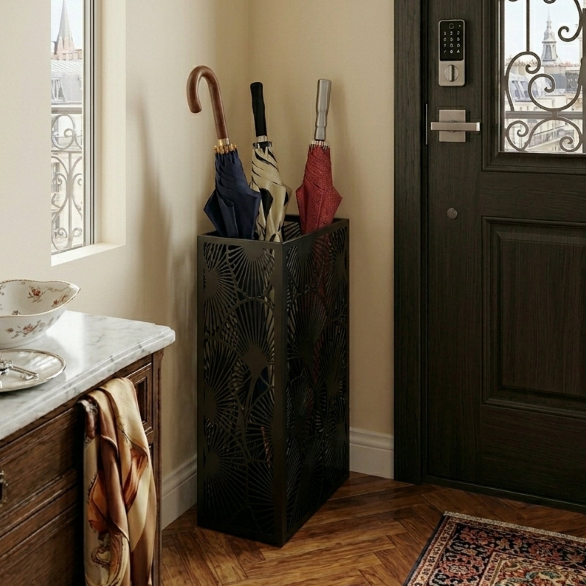 Black leaf pattern metal umbrella stand in classic Parisian entryway with marble counter