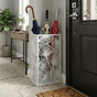 White leaf pattern metal umbrella stand at front door with colorful umbrellas in modern entryway