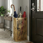 Gold leaf pattern metal umbrella stand in modern entryway with green plant and minimalist decor