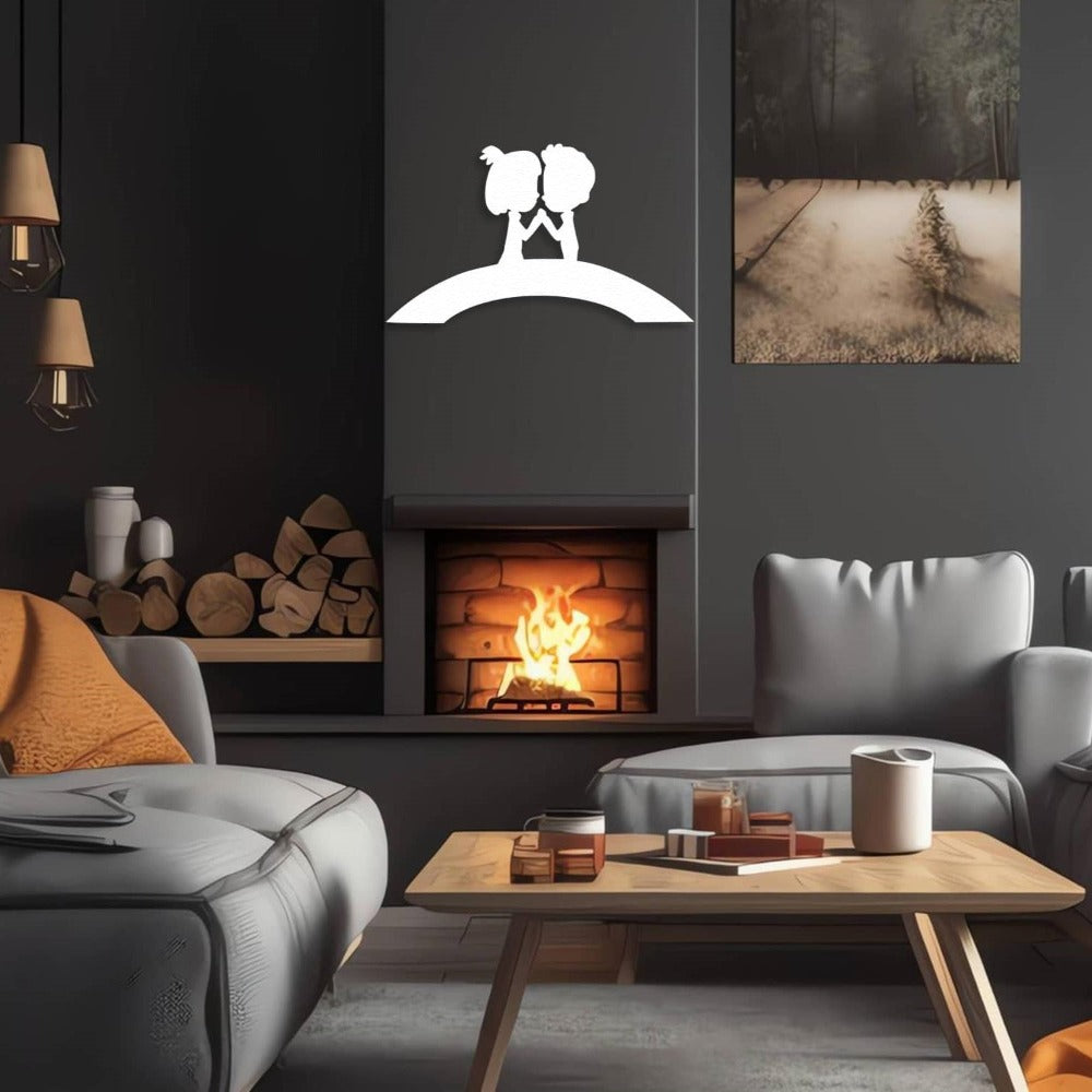White metal wall art of a couple on a bridge, mounted on a dark wall above a cozy fireplace in a modern living room setting.