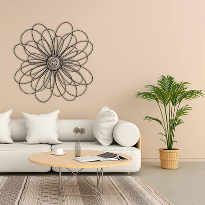 Modern metal daisy wall art displayed above a white sofa in a cozy living room with beige walls and a green potted plant.