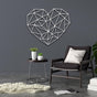 Contemporary geometric heart-shaped metal wall art in elegant white color displayed on a gray wall above a cozy black chair with a white cushion, accompanied by a round side table and decorative plants.